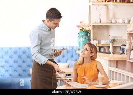 Kellner nimmt Bestellung vom Kunden im Café Stockfoto