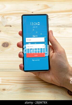 Sicherer Zugriff auf Mobiltelefone. Mann mit Smartphone mit Login, Passwort auf dem Bildschirm, Holzhintergrund Stockfoto