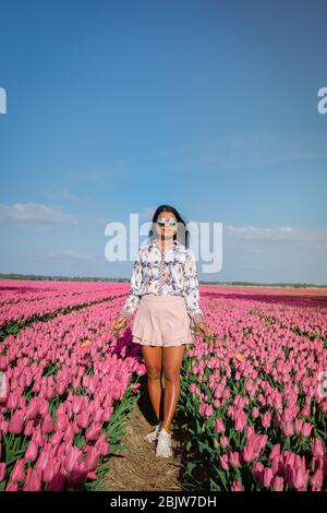 Frau im Blumenfeld, junges Mädchen im Tulpenfeld in den Niederlanden während der Frühjahrssaison an einem hellen sonnigen Tag Stockfoto