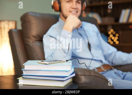 Literatur, Smartphone und verschwommener Mann mit Kopfhörern im Hintergrund. Hörbuch anhören Stockfoto