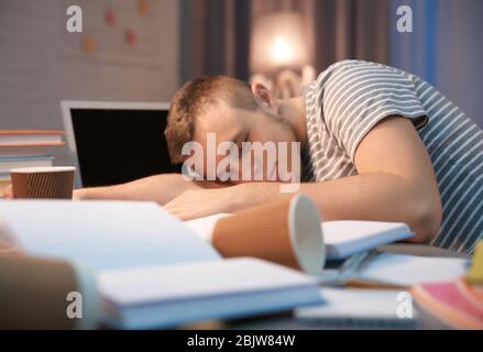 Müde Student schläft am Tisch drinnen Stockfoto