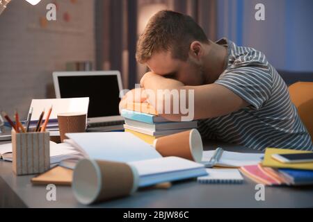 Müde Student schläft am Tisch drinnen Stockfoto
