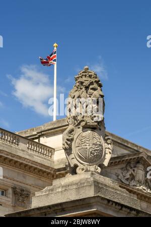 LONDON, ENGLAND - JULI 2018: Skulptur eines Löwen auf einer Säule vor dem Buckingham Palace. Im Hintergrund fliegt die Union Jack Flagge. Stockfoto