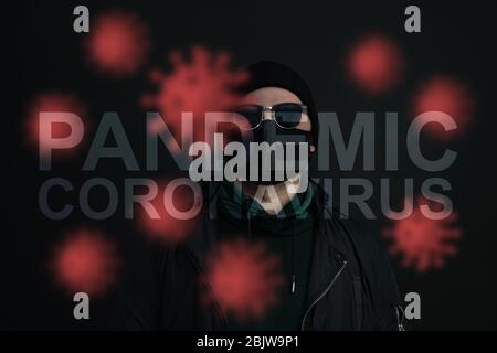 Junger Mann mit Gesichtsmaske. Schöner Mann in schwarzem Hut tragen schwarze medizinische Maske, grauer Hintergrund, Kopie Raum. Pandemische Coronavirus Covid-19 Quarantäne Stockfoto