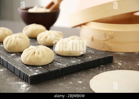 Holzbrett mit rohen Baozi Knödel auf dem Tisch Stockfoto