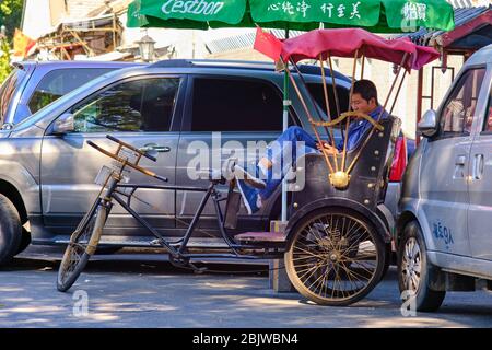 Peking / China - 8. Oktober 2018: Tourist Fahrrad Rikscha Fahrer eine Pause von der Arbeit in Peking, China Stockfoto