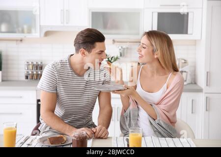 Schöne junge Frau Fütterung ihrer geliebten Freund mit Frühstück in der Küche Stockfoto