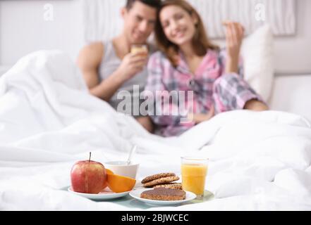 Tablett mit leckeren Frühstück für junge Paare im Bett Stockfoto