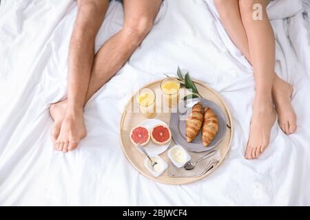 Junges Paar, das zusammen im Bett gefrühstückt hat Stockfoto