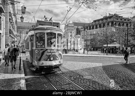 An einem sonnigen Sommertag fährt ein Trolley durch die Straßen von Lissabon, Portugal, nahe dem Praça Luis de Camões Platz. Stockfoto