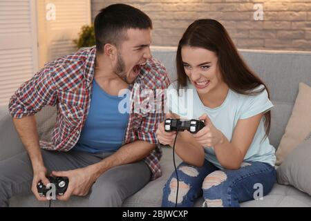 Emotionales Paar auf dem Sofa sitzen und Videospiel zu Hause spielen Stockfoto