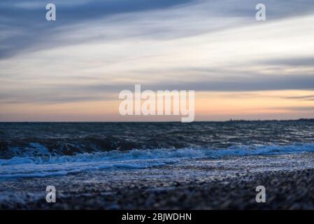 Schöne Welle im Meer am Strand bei Sonnenuntergang. Stockfoto