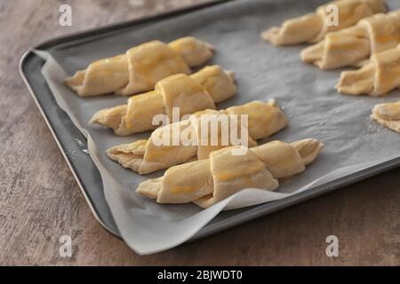Backblech mit rohen Croissants auf dem Tisch, Nahaufnahme Stockfoto