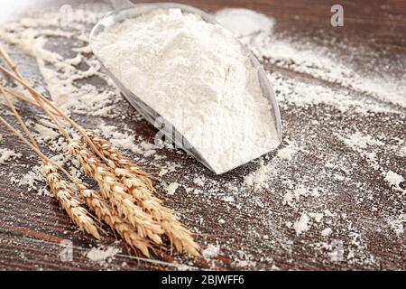 Schaufel mit Weizenmehl und Stacheln auf Holztisch Stockfoto