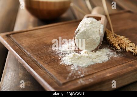 Weizenmehl in Schaufel auf Holzbrett Stockfoto