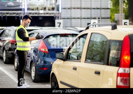 30. April 2020, Niedersachsen, Schüttorf: Ein Mitarbeiter mit Gesichtsmaske weist die Gäste vor Beginn einer Autodisco auf dem Parkplatz der Disco 'Index' an. Zum zweiten Mal bietet die große Diskothek in Grafschaft Bentheim eine Autodisco an. Insgesamt können 500 Gäste an 250 Fahrzeugen teilnehmen. Foto: Hauke-Christian Dittrich/dpa Stockfoto