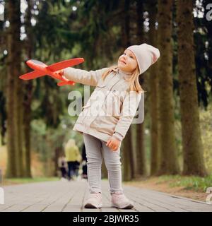 Porträt eines 3-jährigen Mädchens mit einem Spielzeugflugzeug in den Händen im Park Stockfoto