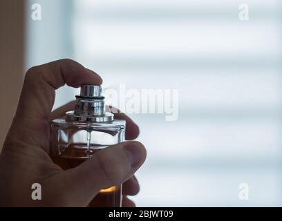 Parfüm aus einer Flasche durch Pressen sprühen Stockfoto