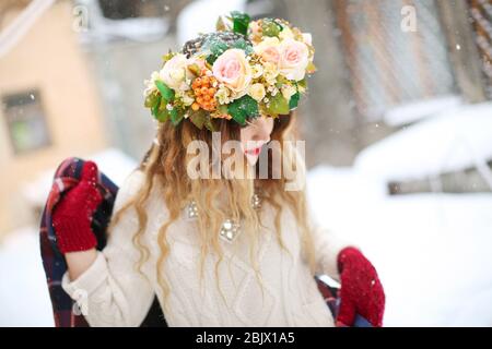 Junge Frau trägt schönen Blumenkranz im Freien am Wintertag Stockfoto