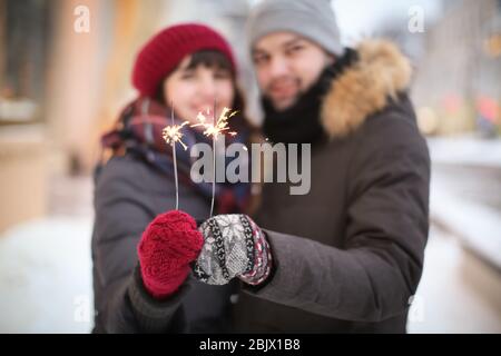 Junge liebende Paar hält Sparklers im Freien am Wintertag Stockfoto