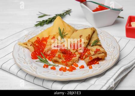 Teller mit dünnen Pfannkuchen und rotem Kaviar auf dem Tisch Stockfoto