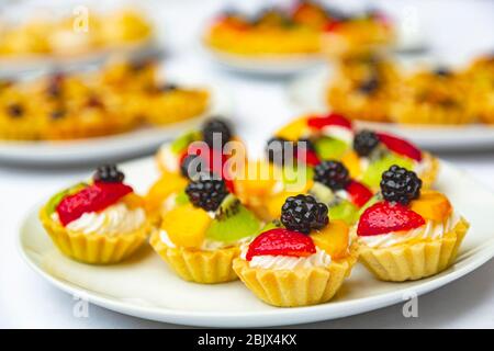 Appetitliche Backwaren in Form von Körben mit Früchten, Beeren und Nüssen auf einem weißen Teller. Candy Bar mit leckeren Cupcakes und Leckereien auf einer Hochzeit p Stockfoto