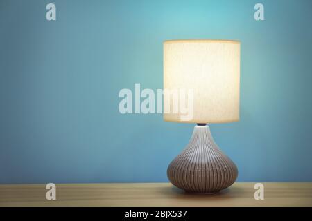 Stilvolle Lampe auf dem Tisch gegen Farbwand Stockfoto