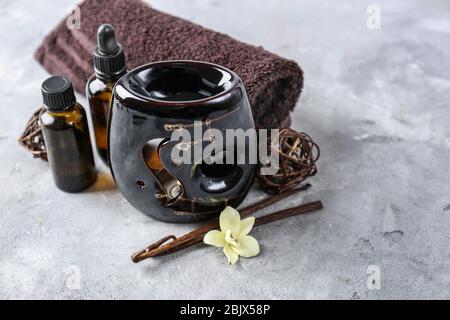 Duftlampe, Handtuch und Ölflaschen auf dem Tisch Stockfoto