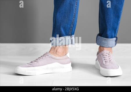 Mann in lässigen Schuhen nahe grauer Wand Stockfoto