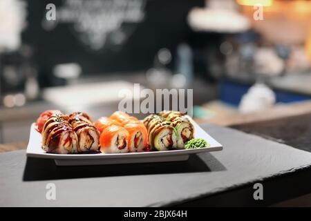 Teller mit leckeren Sushi-Brötchen auf dem Tisch im Restaurant Stockfoto