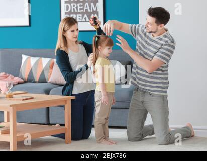 Eltern messen die Höhe ihrer Tochter zu Hause Stockfoto