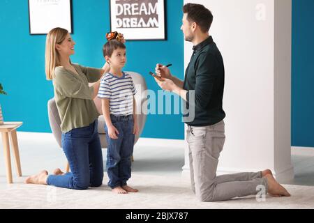 Eltern Messung der Höhe ihres Sohnes zu Hause. Stockfoto