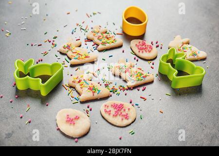 Roher Teig mit Streuseln, Hasen- und eiförmigen Ausstechformen auf grauem Hintergrund. Osterkomposition Stockfoto