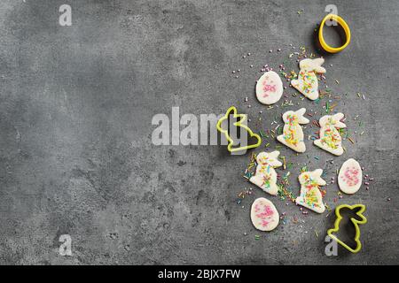 Roher Teig mit Streuseln, Hasen- und eiförmigen Ausstechformen auf grauem Hintergrund. Osterkomposition Stockfoto