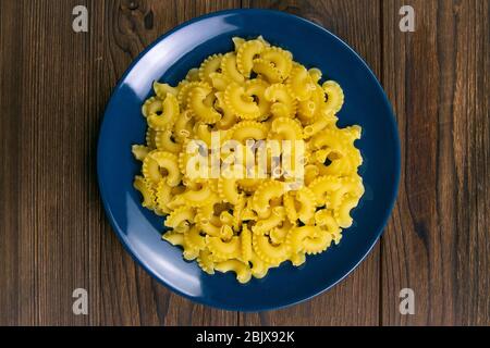 Pene Lisce Pasta in blauer Platte auf dunklem Holzhintergrund. Von oben Stockfoto