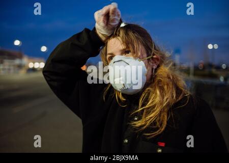 Eine Frau, die während der weltweiten Pandemie Covid-19 eine PSA-Gesichtsmaske und Handschuhe vor einem Lebensmittelgeschäft trägt. Stockfoto