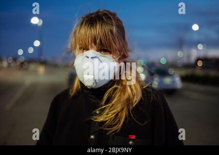 Eine Frau, die während der weltweiten Pandemie Covid-19 eine PSA-Gesichtsmaske und Handschuhe vor einem Lebensmittelgeschäft trägt. Stockfoto
