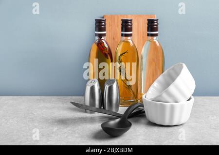 Kochutensilien und Flaschen mit Öl auf dem Tisch Stockfoto