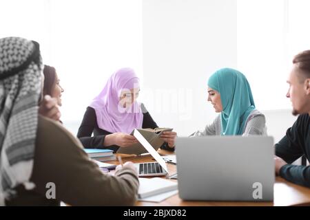 Muslimische Studenten mit ihren Klassenkameraden in der Bibliothek Stockfoto