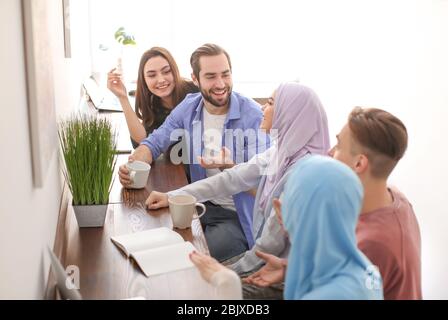Muslimische Studenten mit ihren Klassenkameraden in der Bibliothek Stockfoto