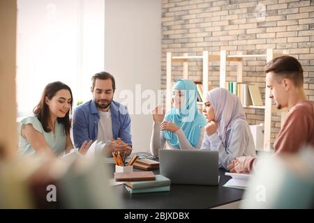 Muslimische Studenten mit ihren Klassenkameraden in der Bibliothek Stockfoto