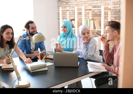 Muslimische Studenten mit ihren Klassenkameraden in der Bibliothek Stockfoto