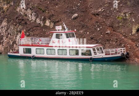 Wuchan, China - 7. Mai 2010: Dicui oder Emerald Gorge am Daning River. Kleines weißes Passagierboot, das am braunen, unbefestigten Berghang auf gree festgemacht ist Stockfoto