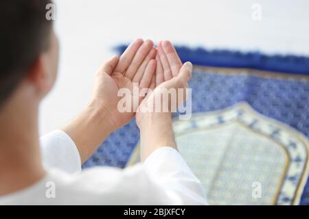 Junger muslimischer Mann, der auf dem Boden betet Stockfoto