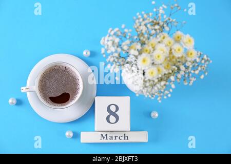 Holzblock Kalender, Tasse Kaffee und Blumen auf farbigen Hintergrund. Feier zum Internationalen Frauentag Stockfoto