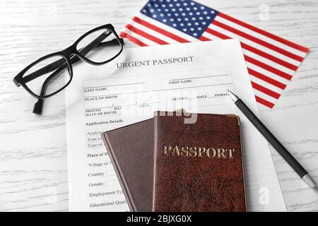 Pässe, Antragsformular und amerikanische Flagge auf dem Tisch. Einwanderung in die USA Stockfoto