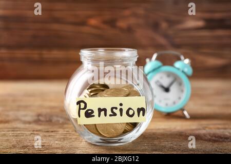 Glas mit Etikett "PENSION" und Münzen auf Holztisch Stockfoto