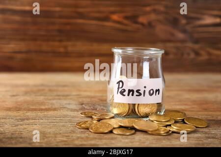 Glas mit Etikett "PENSION" und Münzen auf Holztisch Stockfoto