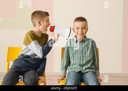 Lustiger kleiner Junge, der seinen Freund mit Megaphon anruft Stockfoto