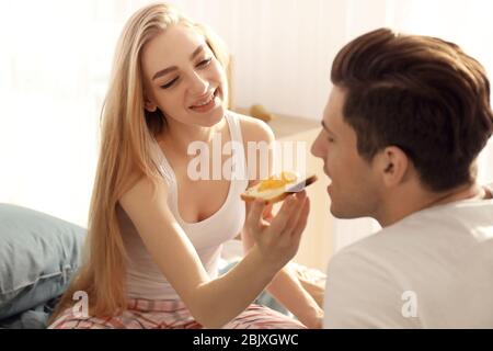 Ein junges, reizendes Paar, das im Bett gefrühstückt hat Stockfoto